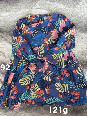 Blommig kortklänning - Färgglad kortklänning från Polarn O. Pyret med blommigt mönster i blått, rosa, gult och grönt. Perfekt för dig som gillar lekfulla och livliga plagg!🌸 Fint använt skick. Storlek 92