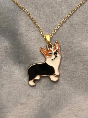 Corgi Halsband Hund Guld imitation   - Så sött halsband med en berlock av en corgi! Berlocken är ca 2 x 2 cm. Trädd på kedja i guldimitation, justerbar 40-45 cm. 