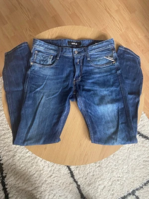 Blåa Replay Jeans - Tjena👋 Säljer ett par klassiska blå jeans från Replay i storlek 30/32📐 Jeansen har fem fickor, snygga slitningar och Replay-logga på bakfickan🪢 De är raka i modellen och har en tidlös tvätt som passar till allt och materialet är slitstarkt jeans👖 Dessa är perfekta till våren!🌅 Om du har frågor: Meddela oss!