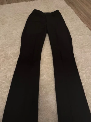 Svarta kostymbyxor från Bik Bok - Snygga svarta kostymbyxor från Bik Bok i klassisk rak modell. Byxorna har midwaist och är tillverkade i ett mjukt material som ger en stilren look. Perfekta att matcha med en cool topp eller hoodie för en trendig vibe.