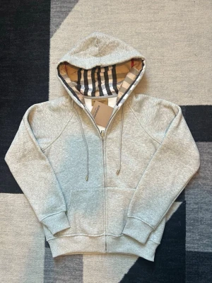 Burberry zip up - Säljer denna burberry zip up som jag har aldrig använt och den var för liten för mig, helt oanvänd med etikett kvar! Tröjan är varm och perfekt för vardagsförbruk! Tröjan har inte heller några tecken på slitage