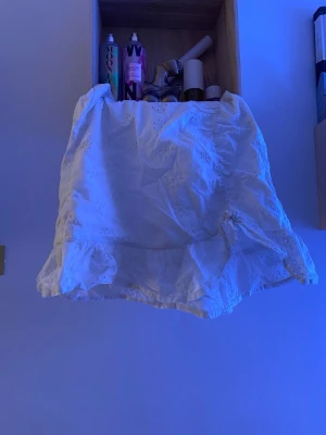 Vit kortkjol med broderade sopmönster H&M - Supersöt vit kortkjol från H&M med volangkant och broderade blommor. Kjolen har resår i midjan och är gjord i mjuk bomull, perfekt för sommarens alla dagar. Säljer då den inte längre kommer till användning!