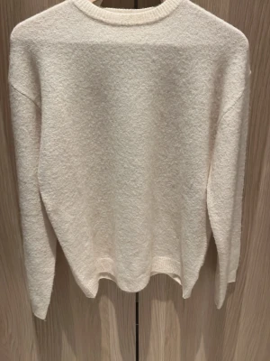Vit stickad tröja från H&M - Mysig vit stickad tröja från H&M i storlek 158/164. Tröjan har rund halsringning, långa ärmar och ribbade muddar vid ärmslut och nederkant. Perfekt för lager på lager under kyliga dagar.