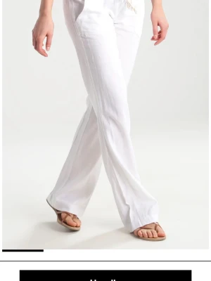 Vita linnebyxor från Roxy - Säljer ett par vita linnebyxor med avslappnad passform . Byxorna har raka ben, fickor fram och bak samt elastisk midja för extra komfort. Perfekta till sommaren och lätta att matcha med olika toppar.