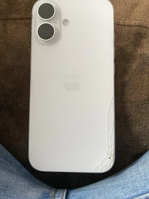iPhone 16 - Snygg vit iPhone 16 med dubbla kameror. Telefonen är fullt fungerande och startar utan problem. Baksidan har dock en spricka i det nedre högra hörnet, men detta påverkar inte användningen. Perfekt för dig som vill ha en modern iPhone till ett bra pris.