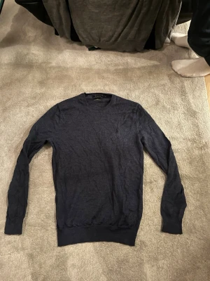 Mörkblå merinoullströja Polo Ralph Lauren - Slim fit mörkblå tröja från Polo Ralph Lauren i tvättbar merinoull. Klassisk rund halsringning och långa ärmar. Perfekt för dig som gillar stilrena och bekväma plagg med en exklusiv känsla.