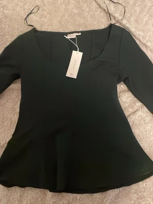 Svart blus - Svart långärmad och urringad blus från Gina tricot 14+ M med  volang med prislapp. 