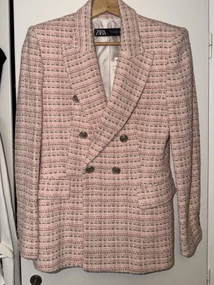 Rutig rosa kavaj från Zara, M - Säljer en snygg rutig kavaj från Zara i rosa och beige toner, storlek M. Kavajen har dubbelknäppning med silvriga knappar och klassisk krage. Materialet är grovt vävt och ger en lyxig känsla. 