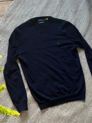 Mörkblå stickad tröja från Ralph Lauren - Säljer en mörkblå stickad tröja från Ralph Lauren i 100% merinoull. Tröjan är i mycket fint skick, 9–10, och har endast använts ett fåtal gånger. Nypris ca 2 500 kr. Storlek S. Personen på bilden är 180 cm lång, men tröjan passar även dig som är cirka 170–180 cm beroende på hur du vill att den ska sitta. Riktigt fin kvalitet och väldigt skön att bära.  Hör av dig vid frågor, för fler bilder. Pris kan diskuteras vid snabb affär.