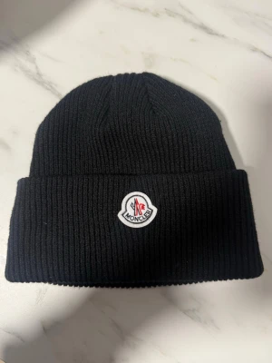 Moncler mössa - Moncler mössa äkta, se sista bild. Varm. Endast använd en gång. Inga defekter.
