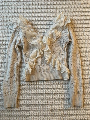 Beige stickad topp med volanger från Zara - Beige stickad topp från Zara med långa ärmar och v-ringning. Tröjan har detaljerade volanger. Ettiketten har nästan åkt av. 