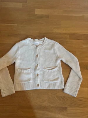 Vit kofta med fickor och knappar - Vit kofta med två fickor och guld knappar. Använd 2 gånger, jättebra skick. Från gina tricot young storlek 134/140