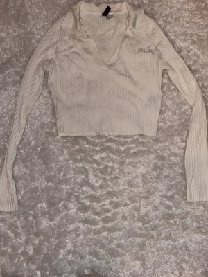 Vit  ribbad croppad polotopp från HM - Säljer en vit croppad polotopp från HM med ribbad struktur och lång ärm. Toppen har en snygg v-ringad öppning. använd fåtal gånger, stl S, köparen står för frakt☺️