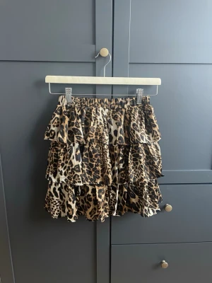 Leopardmönstrad volangkjol - Säljer en kort kjol med leopardmönster, med flera lager volanger. Kjolen är elastisk i midja och är i storlek S/M men skulle mer säga XS/S. Använd fåtal ggr. Nypris 499kr. Skriv vid intresse! 💕