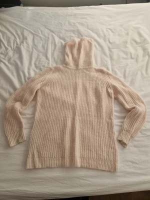 Beige stickad hoodie från Zara Knit - Säljer en beige stickad hoodie från Zara Knit i storlek M. Tröjan har lång ärm, ribbade muddar och en stor huva. Materialet är mjukt och fluffigt, perfekt för kyliga dagar. Enkel och stilren design som är lätt att matcha med andra plagg.