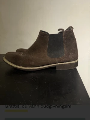 Bruna chelsea boots i mocka - Säljer ett par bruna chelsea boots i mocka från Playboy. Perfekt för en avslappnad men stilfull look. Välanvända men sliten innersula . 