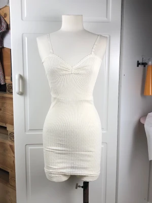 Vintage set underkläder - En vintage underklänning med smala axelband och en matchande underbyxa med korta ben. Klänningen har v-ringning med rynk framtill. Båda plaggen har en ribbad textur med smått mönster och är mycket stretchiga. Passar både små och stora storlekar. Settet kommer i en originalkartong.