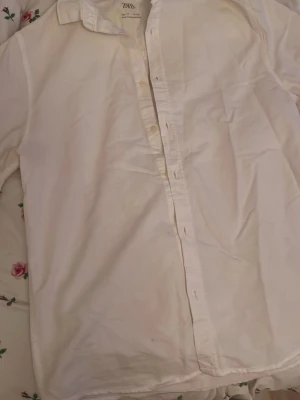 Vit skjorta från Zara, storlek 14 - Klassisk vit skjorta från Zara i storlek 14, med krage och långa ärmar. Skjortan har knappar hela vägen framtill och vid manschetterna. Aldrig använd 