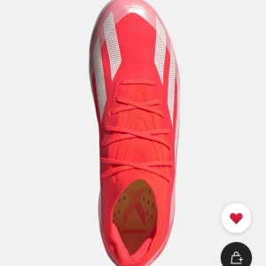 Adidas Crazyfast elite röda fotbollsskor ag - Säljer ett par Adidas Crazyfast fotbollsskor i en riktigt snygg röd färg med vita ränder på sidorna. Skorna har snörning och en rund tå, samt en lätt och ventilerande ovandel i syntetmaterial. Perfekt för dig som vill sticka ut på planen.