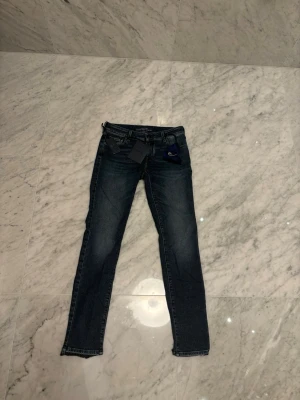 Jacob Cohen mörkblå jeans helt nya - Snygga mörkblå jeans från Jacob Cohen med klassisk femficksdesign och diskreta slitningar. Modellen har normal passform och raka ben, med detaljer som märkets logga på etiketten och en blå tygpåse i midjan. Perfekta för dig som gillar stilrena jeans med exklusiv känsla. Sprillans nya!