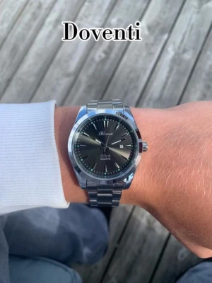 Silverfärgad Svart x Doventi klocka  - 🌟 Doventi - Helt ny och oanvänd klocka i toppskick! 🌟 🎁 Levereras komplett med originalbox. ✨ Perfekt skick, garanterat utan defekter. ⚙️ Enkel justering för optimal passform. 🚀 Snabb leverans samma dag – direkt till dig!