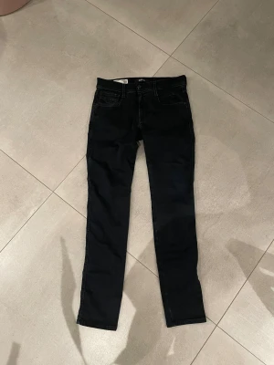 Replay Anbass svarta jeans - Tja säljer nu ett år riktigt snygga Svarta Replay Anbass hyperflex🤯jeans med slim passform och klassisk femficksdesign. Jeansen har en snygg mörk tvätt, smal siluett och är tillverkade i stretchigt bomullsmaterial för extra komfort. Perfekt för dig som gillar stilrena och moderna jeans dessa jeans passar till allt och har de detaljerna som man kan tro att du är världens rikaste person🤩skicket är perfekt ungefär som nytt storlek w30/l32 passar dig som är typ 175-183, hör av dig vid fråga!! Mvh EM
