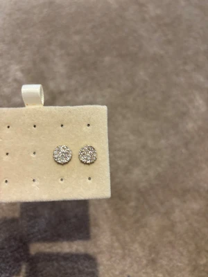 Glittriga runda örhängen i guld - Säljer ett par snygga runda örhängen med guldfärgad bas och massor av små gnistrande stenar på framsidan. De har klassisk stiftbaksida och är perfekta för att ge lite extra bling till din look. Passar dig som gillar stilrena men ändå iögonfallande accessoarer. Säljer då jag inte använder dom!