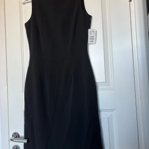 Svart klassisk klänning - Fin klassisk svart klänning från H&M. I nyskick, med prislapp kvar. Underklänning inuti. Dold dragkedja baktill. Storlek 34. Originalpris: 298kr. 