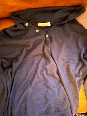 Mörkblå hoodie från Luca faloni i kashmir - Säljer en mörkblå hoodie från luca faloni i kasmir. Tröjan har huva, knappar vid halsen och en clean look utan tryck. Perfekt för dig som gillar stilrena och exklusiva plagg. Ny pris : 2500-3000 kr