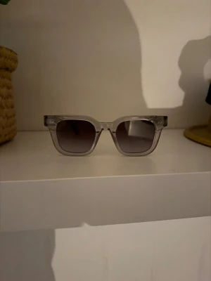 Transparenta solglasögon - Snygga solglasögon med transparent plastbåge och fyrkantig form. Glasen är mörktonade och ger en cool vibe till din look. Perfekt för dig som gillar stilrena accessoarer med en modern touch.