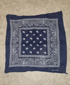 Marinblå paisley halsduk i bomull - Snygg marinblå halsduk med klassiskt paisleymönster i vitt. Tillverkad i 100% bomull, perfekt att knyta runt halsen eller använda som accessoar. Fyrkantig form och mjukt material som känns skönt mot huden.