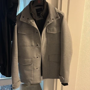 Grå overshirt från Jack & Jones XS - Snygg grå overshirt från Jack & Jones med fyra stora fickor framtill, klassisk krage och knappar. Jackan har en stilren look och är fodrad på insidan för extra värme. Perfekt för lager-på-lager och enkel att matcha med det mesta. jackan är i XS men passar även S.