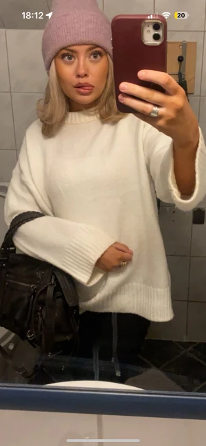 Vit stickad oversized tröja - Säljer en vit stickad tröja med breda ribbade muddar vid ärmslut och nederkant. Tröjan har en loose och oversized passform med långärmade ärmar och rund hals. Perfekt för dig som gillar en chill och enkel stil.