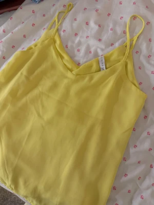 Gul linnetopp XS - gul linnetopp från Amisu i storlek XS. Toppen har tunna axelband och en lätt v-ringad halsringning.