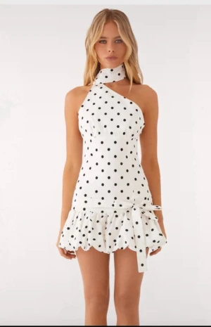 Vit prickig miniklänning med volang - Supersöt vit miniklänning med svarta prickar och volangkant nertill. Klänningen har oneshoulder-modell med hög hals och knyt i midjan. Köpes för runt 900 från Peppermayo och använd väldigt sparsamt, jättebra skick!💖