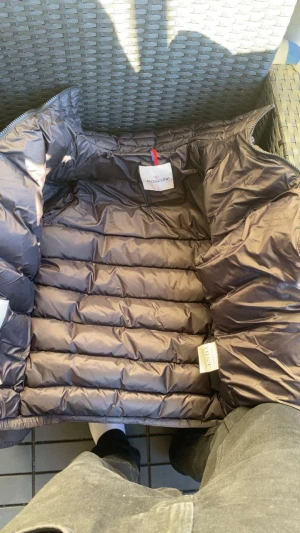 Svart Moncler jacka - Säljer en svart jacka från Moncler med klassisk puffer-design. Jackan har dragkedja framtill, snedställda fickor med dragkedja och Moncler-logga på ärmen. Materialet är glansigt och syntetiskt, perfekt för kalla dagar.