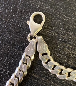 Kedjearmband i äkta silver 925 - Snyggt kedjearmband i äkta silver 925 med klassisk karbinlås. Länkarna är platta och breda för en cool och stilren look. Perfekt längd för handleden, ca 20 cm. Märkt med 925 på låset. Passar dig som gillar tidlösa smycken med lite edge. 10 gram