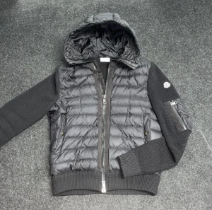 Moncler cardigan  - Svart moncler cardigan storlek M med stickade ärmar och quiltad kropp. Jackan har huva, dragkedja framtill och ribbade muddar. På ena ärmen finns en ficka med dragkedja och Moncler-logga. Perfekt för dig som gillar streetstyle och vill ha något som sticker ut. Svarar alla meddelanden direkt och fraktar alltid samma dag som köp:)