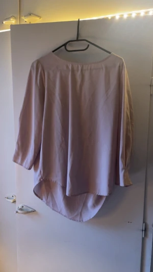 Beige blus med rund hals - Säljer en enkel och stilren beige blus med rund hals och trekvartsärm. Blusen har en längre bakdel som ger en snygg siluett och är gjord i ett mjukt, lätt material. Perfekt för dig som gillar minimalistisk stil och neutrala färger.