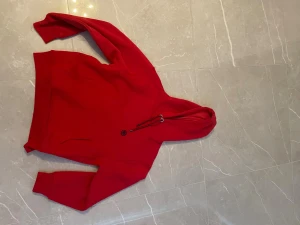 Röd hoodie från Mavi med huva - Snygg röd hoodie från Mavi med stor huva och dragsko i rött och svart. Klassisk känguruficka framtill och ribbade muddar vid ärmar och nederkant. Mjuk insida i fleece och stilren design, perfekt för chill dagar. Märke: Mavi 1991.