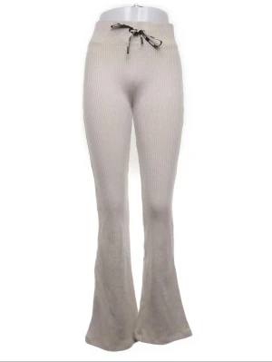 Stronger tränings tajts Beige ribbade bootcut-byxor Stronger - Snygga beige ribbade byxor från Stronger i bootcut-modell . Mjukt material i bomull och polyester som ger en skön känsla. Perfekta för chill eller träning, med stilren look och bekväm passform. Stl xs. 