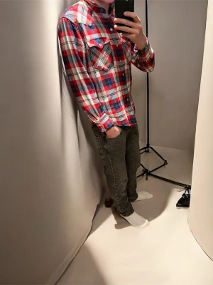 Rutig röd och blå skjorta från Levis - Säljer en snygg rutig skjorta i rött, blått och vitt med klassisk krage och två bröstfickor med lock. Skjortan har långa ärmar och knappar framtill samt vid ärmslut. Perfekt för dig som gillar en chill och avslappnad stil. Tröjan är nästan aldrig använd. Skriv om du undrar över något.