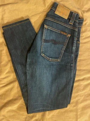 Mörkblå Nudie Jeans slimfit - Säljer ett par mörkblå jeans från Nudie Jeans med sjuk tvätt. Jeansen är slimfit och W29/L32🔥 Jeansen är i mycket bra skick med inga defekter, modellen på bilden är 178cm och 63kg👌Bara att höra av dig vid andra frågor👑