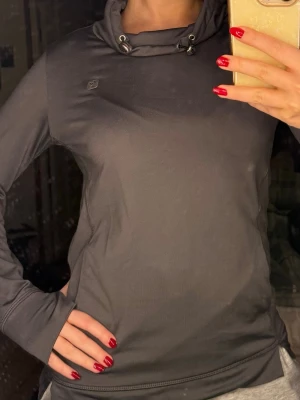 Träningstopp från Freddy D.I.W.O - Jätteskön och snygg träningströja från Freddy D.I.W.O. Perfekt att springa i och den har en fick på baksidan där man kan lägga ner saker och det finns även spännband för att packa ihop den liten eller spänna fast saker. Finns även spännen vid halsen för att tajta till när det tex är kallt ute.