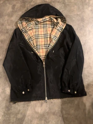Burberry windbreaker - En snygg helt ny aldrig använd burberry vindjacka. Jackan har två olika sidor ena svart och den andra i burberry mönster nypris på jackan är 3500. Pris kan diskuteras