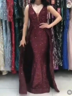 Vinröd glittrig långklänning - Säljer en vinröd långklänning med glittriga detaljer och djup v-ringning. Klänningen har ärmlös design och figurnära passform som framhäver siluetten. Perfekt för bal eller festliga tillfällen där du vill sticka ut.