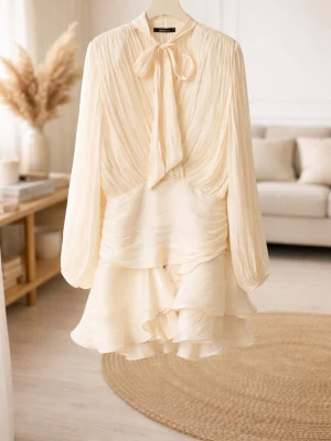 Frill klänning Gina tricot  - Säljer en champagnefärgad kortklänning från Gina tricot med omlott-design, volangdetaljer och knytband i halsen. Klänningen har långa ärmar och är tillverkad i ett lätt, glansigt material som ger en lyxig känsla. Perfekt för dig som gillar romantisk och elegant stil. —> ordinarie pris: 599kr och den är helt ny med prislapp💕