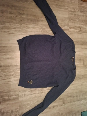Blå stickad tröja med v-ringning - Mörkblå stickad tröja från G-star raw med v-ringad hals och ribbade muddar. Rutmönster på armbågarna. Bra skick men har andvänds några gånger. Storlek M med loose fit. Köptes för ca 1000kr, priset kan förhandlas!