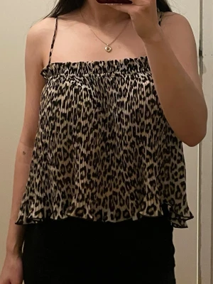 Leopardmönstrad linnetopp från H&M - Säljer en luftig och plisserad linnetopp från H&M i storlek S. Toppen har leopardmönster i beige och svart, tunna axelband och smock upptill. Perfekt för dig som gillar djurmönstrat och vill ha en cool och trendig look<3
