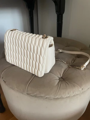 Vit quiltad axelväska med kedja - Snygg axelväska i vit färg med quiltad design och guldfärgad kedjerem. Så himla snygg! Inga tecken på användning! 